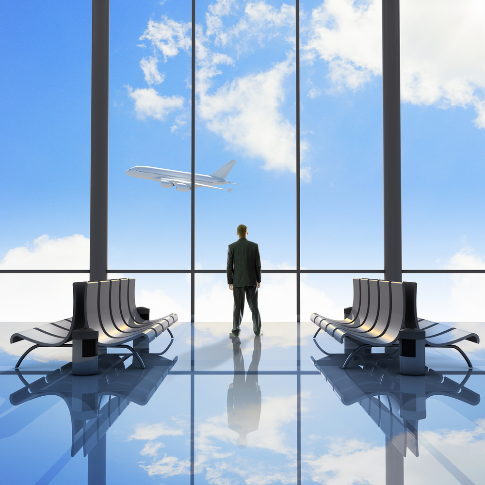 Businessman at airport looking at airplane taking off